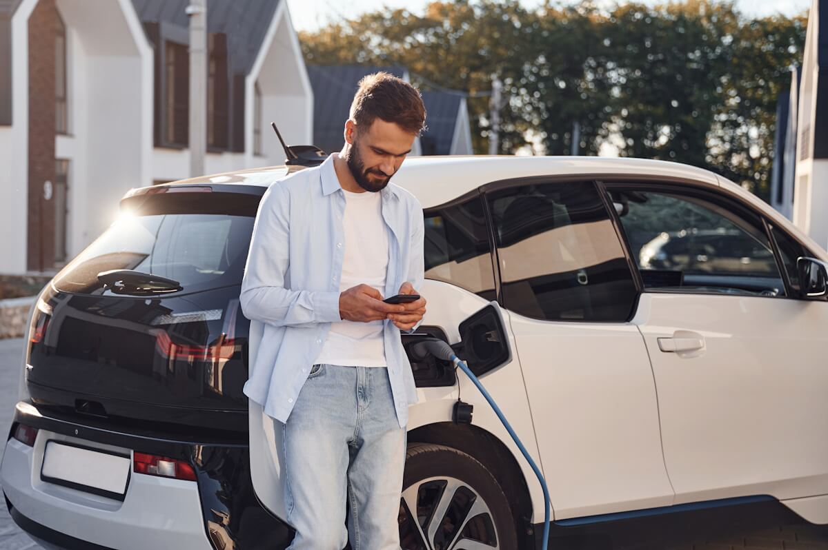 mężczyzna_ładuje_samochód_elektryczny_na_parkingu_na_osiedlu_mieszkalnym
